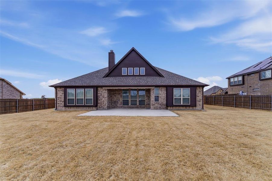 Back of property featuring brick siding, a patio area, a chimney, a fenced backyard, and roof with shingles