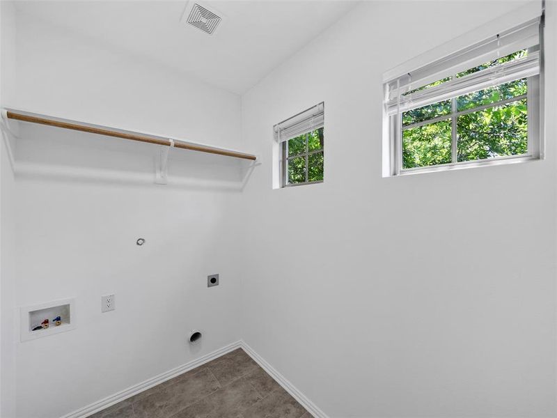 Washroom with hookup for an electric dryer, hookup for a washing machine, and tile patterned floors