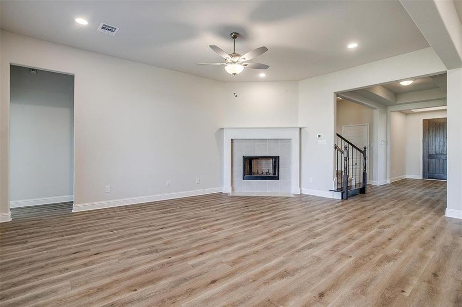 Unfurnished living room featuring a tile fireplace, ceiling fan, and light hardwood / wood-style flooring