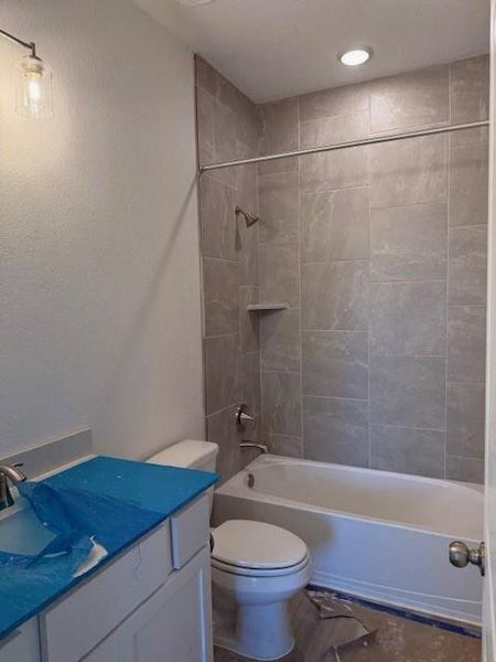 Bathroom featuring bathing tub / shower combination, vanity, and a textured wall Bathroom featuring bathing tub / shower combination, vanity, and a textured wall