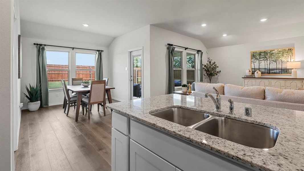 This open-concept living space features light wood flooring, recessed lighting, and large windows that provide views of the backyard