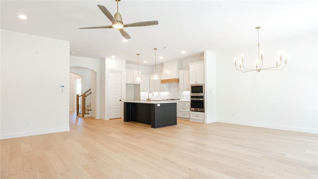Kitchen with open floor plan, light wood-type flooring, light countertops, oven, and recessed lighting Kitchen with open floor plan, light wood-type flooring, light countertops, oven, and recessed lighting