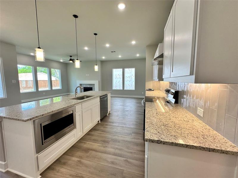 Kitchen featuring tasteful backsplash, a kitchen island with sink, stainless steel appliances, and light stone counters