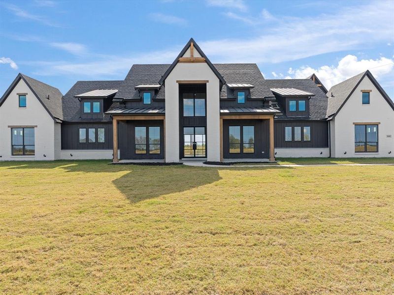 Rear view of house featuring a standing seam roof, a metal roof, and a yard Rear view of house featuring a standing seam roof, a metal roof, and a yard