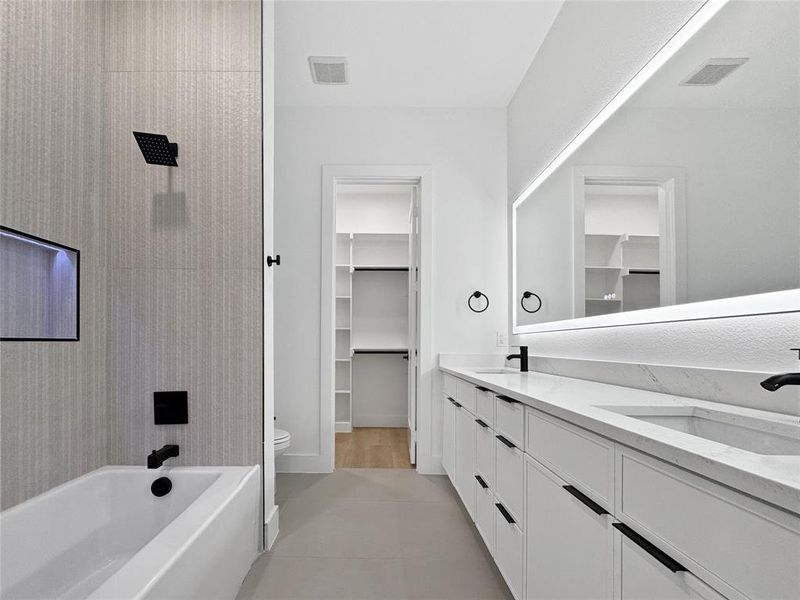 Full bathroom with double vanity, shower / tub combination, a spacious closet, and light tile patterned floors