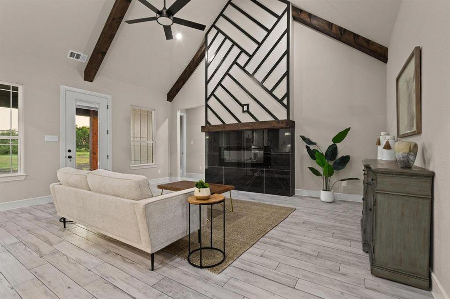 Living area with high vaulted ceiling, beam ceiling, ceiling fan, and light wood finished floors