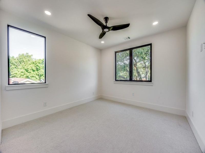 Spare room featuring a healthy amount of sunlight, ceiling fan, and light colored carpet