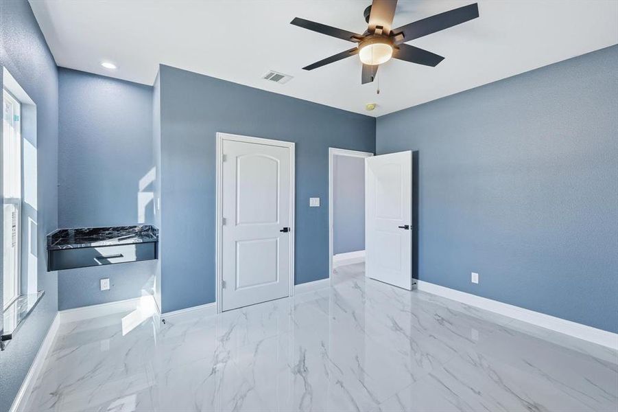 Unfurnished bedroom with light marble finish floors and a ceiling fan