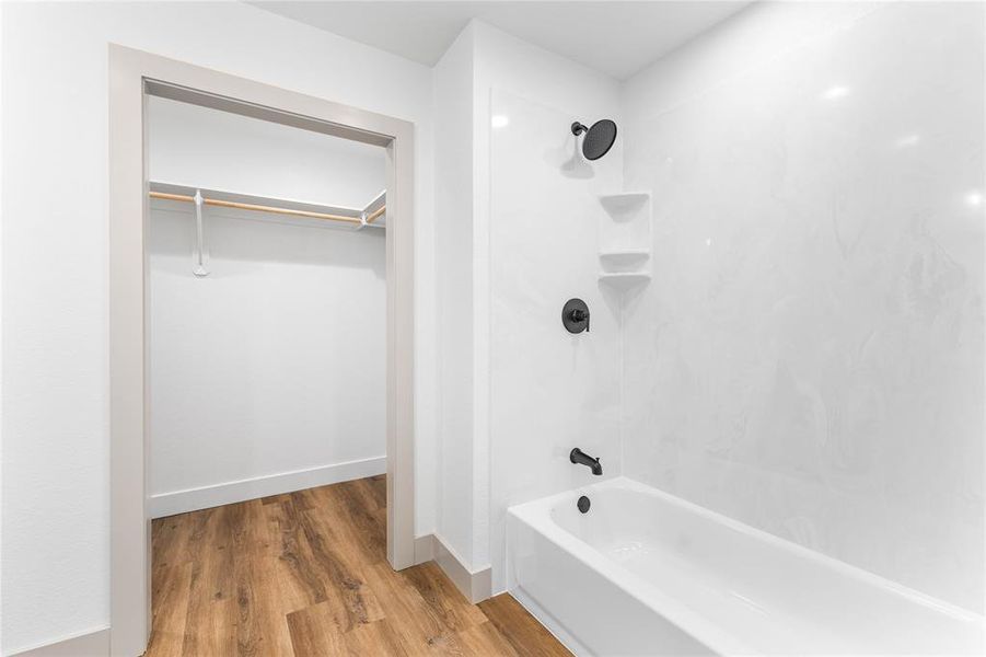 Full bathroom featuring shower / washtub combination, light wood-style flooring, and a walk in closet Full bathroom featuring shower / washtub combination, light wood-style flooring, and a walk in closet