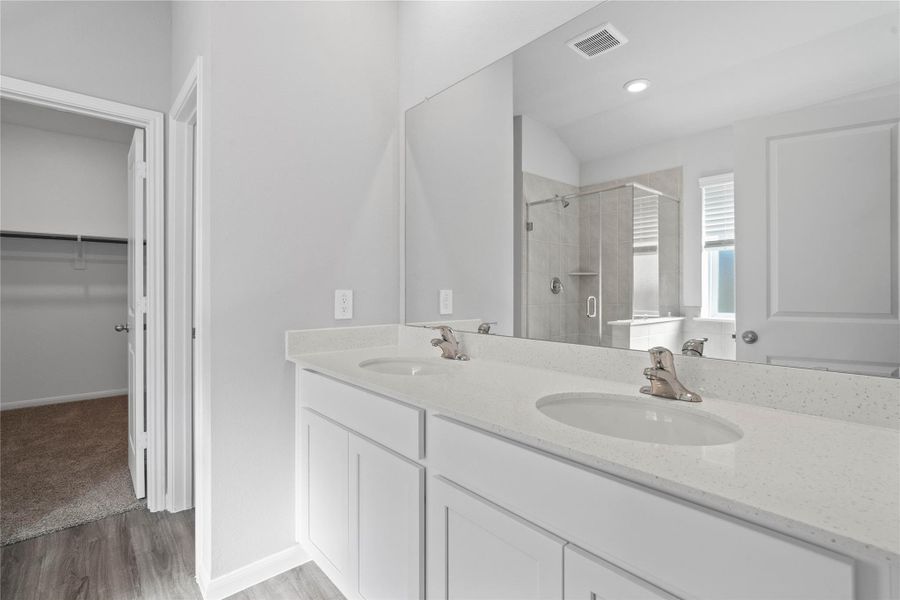 A bright and functional primary bath offering dual sinks for busy mornings, a large mirror, soaking tub, and a modern glass-enclosed shower, creating a serene and efficient space. A bright and functional primary bath offering dual sinks for busy mornings, a large mirror, soaking tub, and a modern glass-enclosed shower, creating a serene and efficient space.