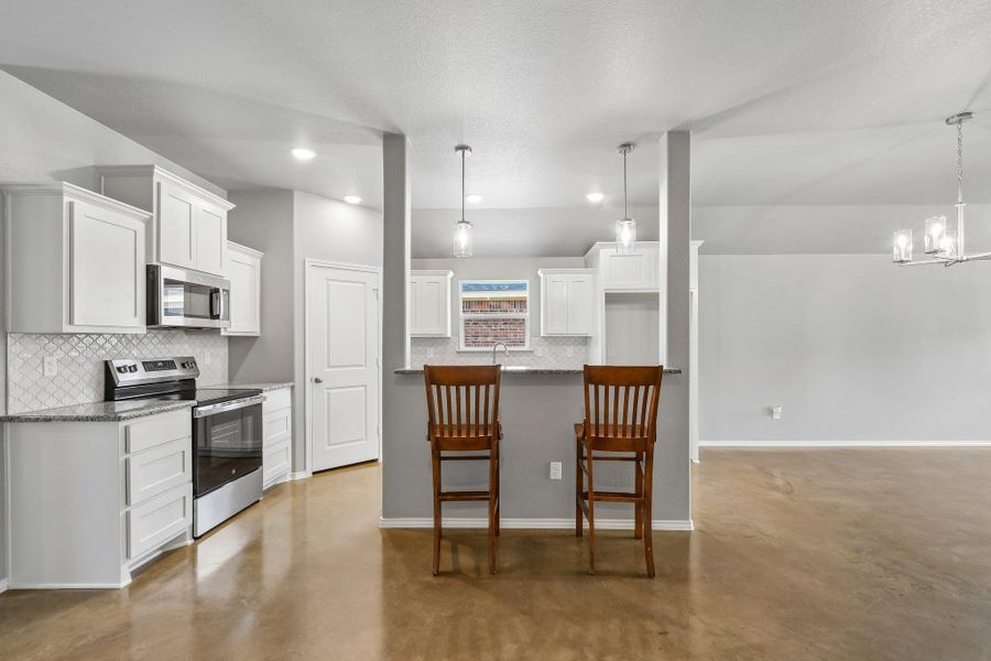 A contemporary kitchen features bright white cabinetry, stainless steel appliances, and a convenient breakfast bar. A contemporary kitchen features bright white cabinetry, stainless steel appliances, and a convenient breakfast bar.