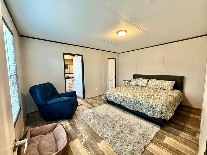 Bedroom featuring wood finished floors, ornamental molding, and connected bathroom