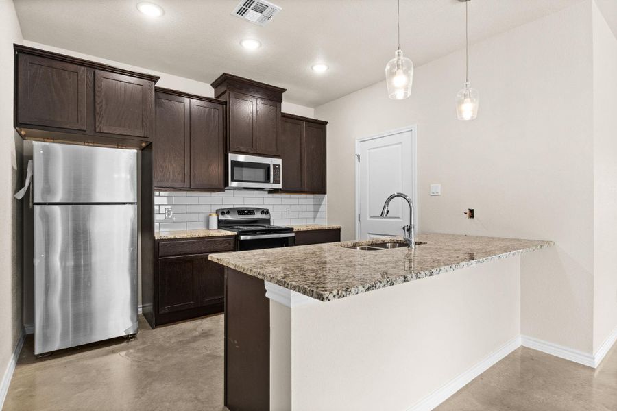Kitchen with finished concrete floors, stainless steel appliances, dark brown cabinetry, light stone counters, and recessed lighting