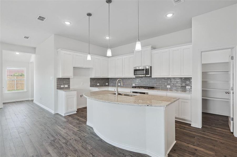 Kitchen with a kitchen island with sink, appliances with stainless steel finishes, dark wood-type flooring, and white cabinetry