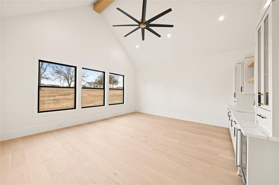 Spacious room featuring a vaulted ceiling with a visible wood beam, recessed lighting, and a contemporary black ceiling fan