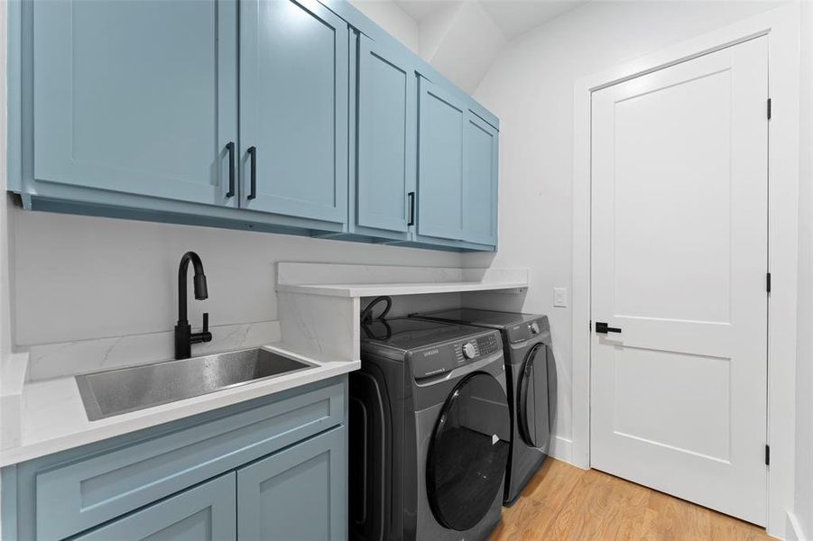 Washroom with light wood-style floors, washer and dryer, and cabinet space Washroom with light wood-style floors, washer and dryer, and cabinet space