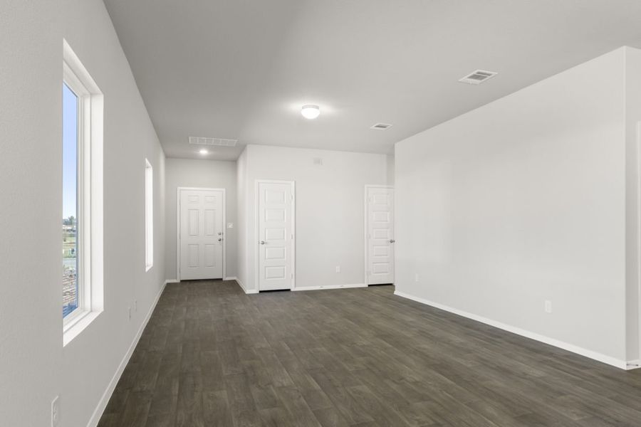 Image of a living room with dark brown floors, light grey walls, a white front door and windows