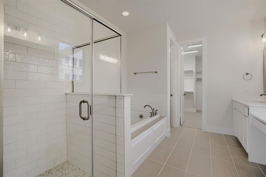 Spacious bathroom featuring a glass-enclosed shower with white subway tile, a built-in soaking tub, and neutral-toned floor tiling