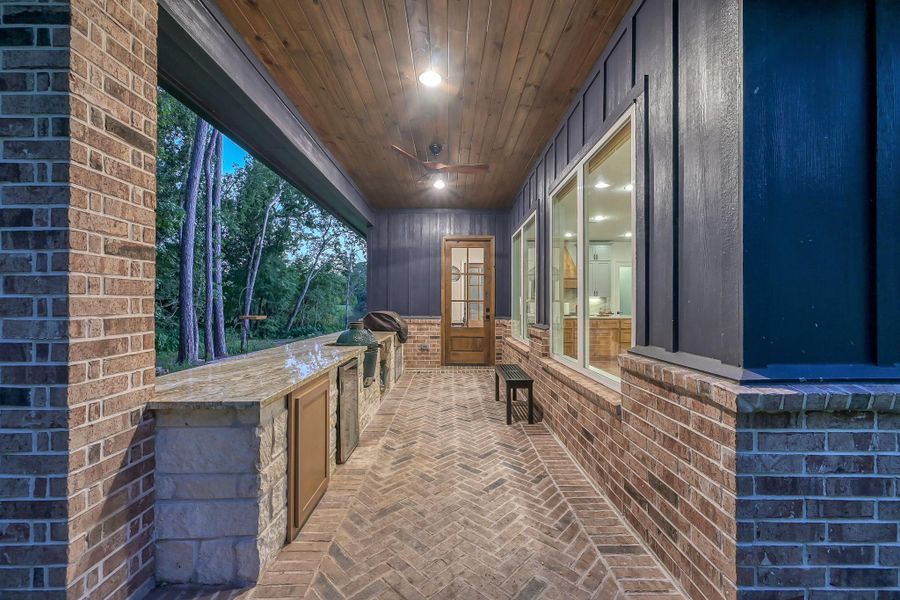 This photo showcases a spacious, covered balcony with a stunning view of a tranquil lake and lush greenery, perfect for enjoying serene sunsets.