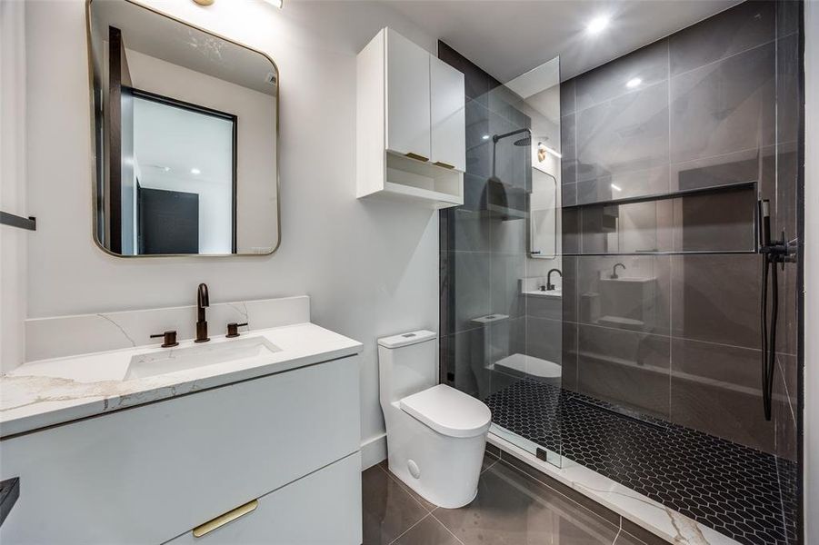 Bathroom with a shower with shower door, vanity, toilet, and tile floors