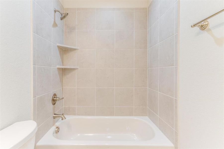 Bathroom with tiled shower / bath combo and toilet