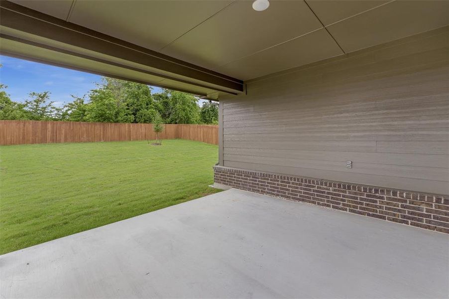 Covered patio with a concrete surface, featuring brick wainscoting and horizontal siding
