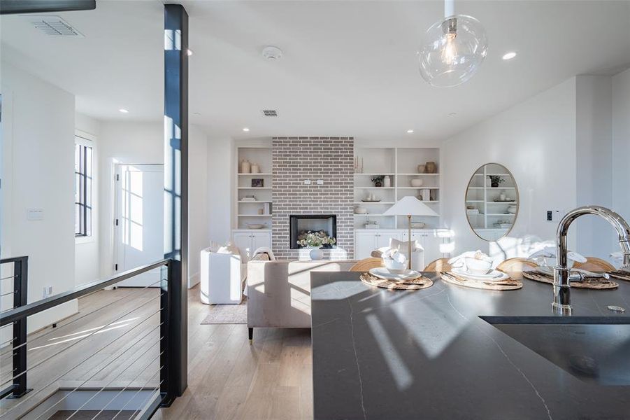 Living room with built in shelves, a fireplace, light hardwood / wood-style floors, and sink