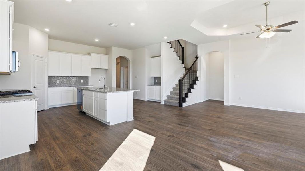 Kitchen with arched walkways, decorative backsplash, light stone countertops, white cabinetry, and recessed lighting Kitchen with arched walkways, decorative backsplash, light stone countertops, white cabinetry, and recessed lighting