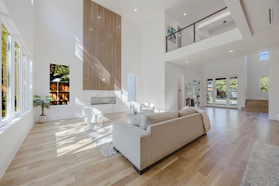 Living area featuring light wood finished floors, a towering ceiling, and recessed lighting Living area featuring light wood finished floors, a towering ceiling, and recessed lighting