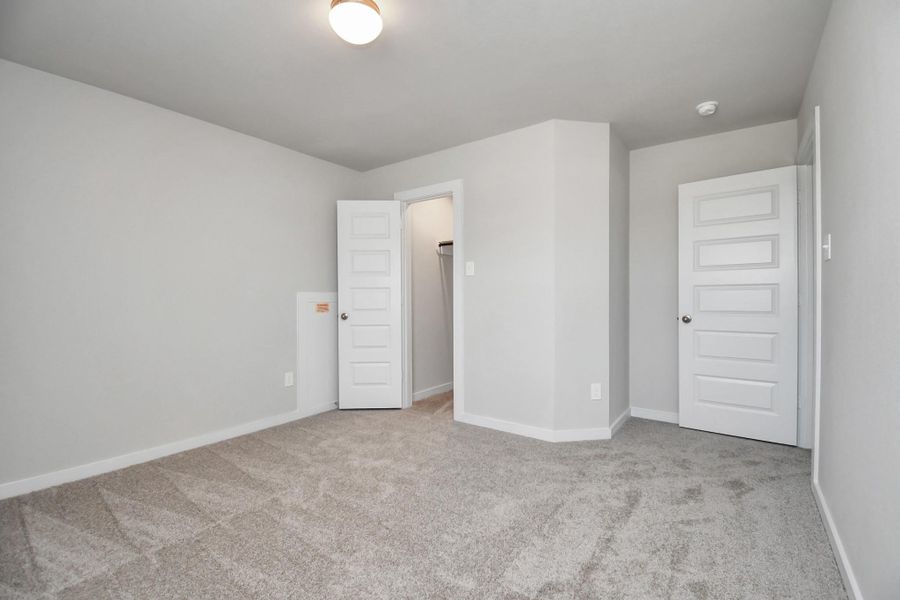 Secondary bedrooms showcase 5-panel doors adorned with modern hardware, large windows enhanced by privacy blinds, and spacious closets featuring sleek and contemporary finishes. Sample photo of completed home with similar floor plan. Actual colors and selections may vary.