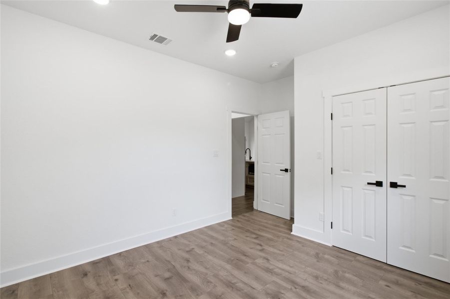 A well-lit bedroom features durable laminate flooring and a modern ceiling fan for comfort. A well-lit bedroom features durable laminate flooring and a modern ceiling fan for comfort.