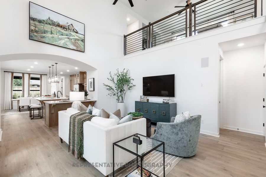 Living room featuring arched walkways, recessed lighting, light wood finished floors, ceiling fan, and a towering ceiling Living room featuring arched walkways, recessed lighting, light wood finished floors, ceiling fan, and a towering ceiling
