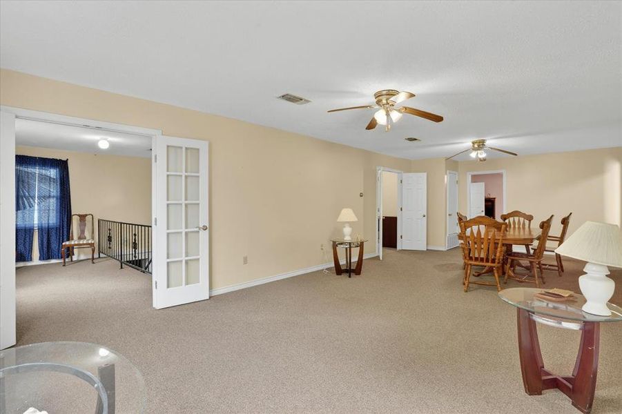 Spacious carpeted living room featuring multiple ceiling fans and neutral wall tones