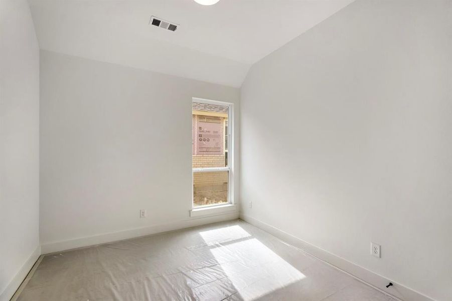 Spare room featuring vaulted ceiling and baseboards