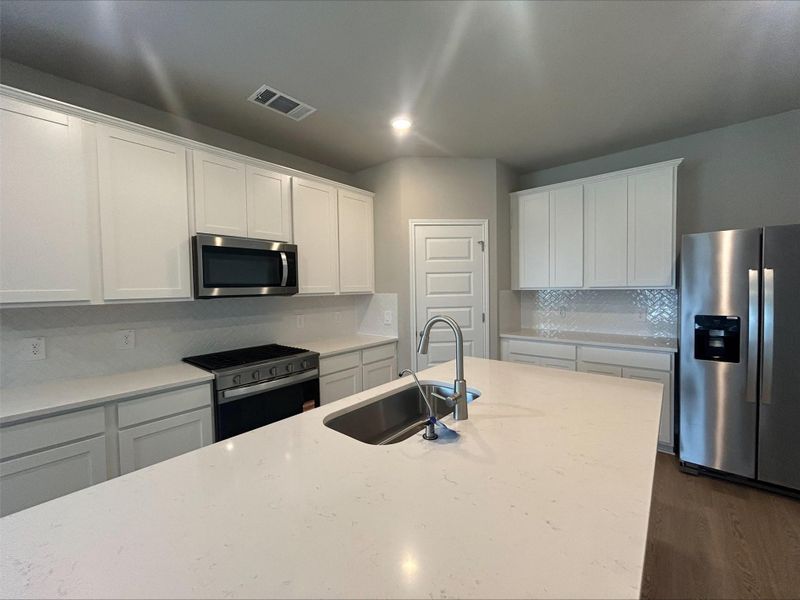 Kitchen featuring stainless steel appliances, dark wood-type flooring, decorative backsplash, white cabinets, and recessed lighting Kitchen featuring stainless steel appliances, dark wood-type flooring, decorative backsplash, white cabinets, and recessed lighting