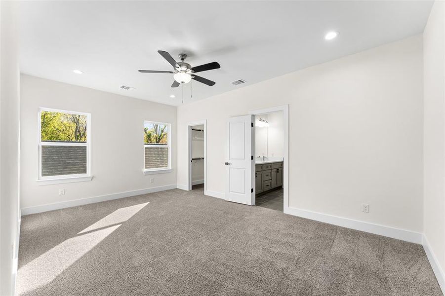 Unfurnished bedroom with a spacious closet, recessed lighting, light colored carpet, ceiling fan, and connected bathroom Unfurnished bedroom with a spacious closet, recessed lighting, light colored carpet, ceiling fan, and connected bathroom