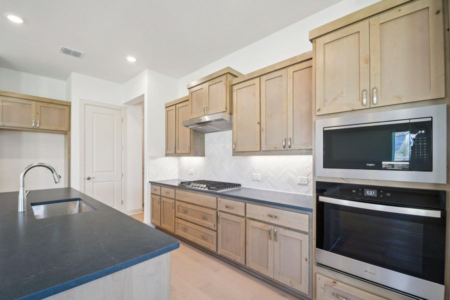 Kitchen featuring stainless steel appliances, tasteful backsplash, light wood-style flooring, recessed lighting, and light brown cabinetry Kitchen featuring stainless steel appliances, tasteful backsplash, light wood-style flooring, recessed lighting, and light brown cabinetry