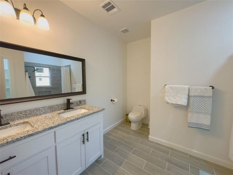 Bathroom with dual vanity, tile flooring, and toilet