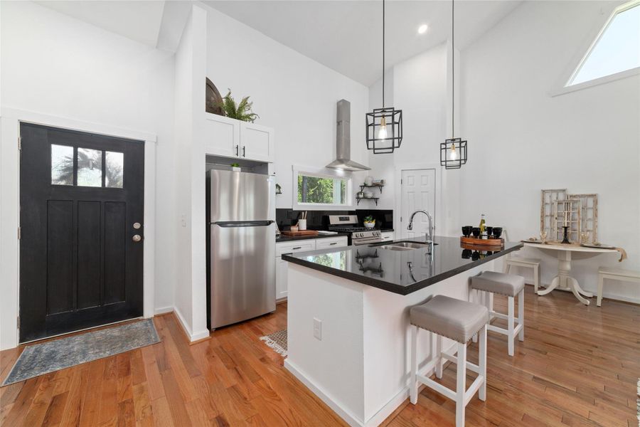 This kitchen features a modern design with white cabinets, stainless steel appliances, black granite counters and a central island with seating. This kitchen features a modern design with white cabinets, stainless steel appliances, black granite counters and a central island with seating.