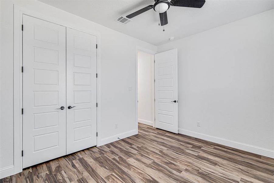 Unfurnished bedroom featuring wood-type flooring, a closet, and ceiling fan