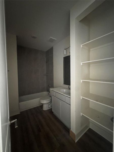 Bathroom featuring vanity, bathing tub / shower combination, and dark wood-type flooring Bathroom featuring vanity, bathing tub / shower combination, and dark wood-type flooring