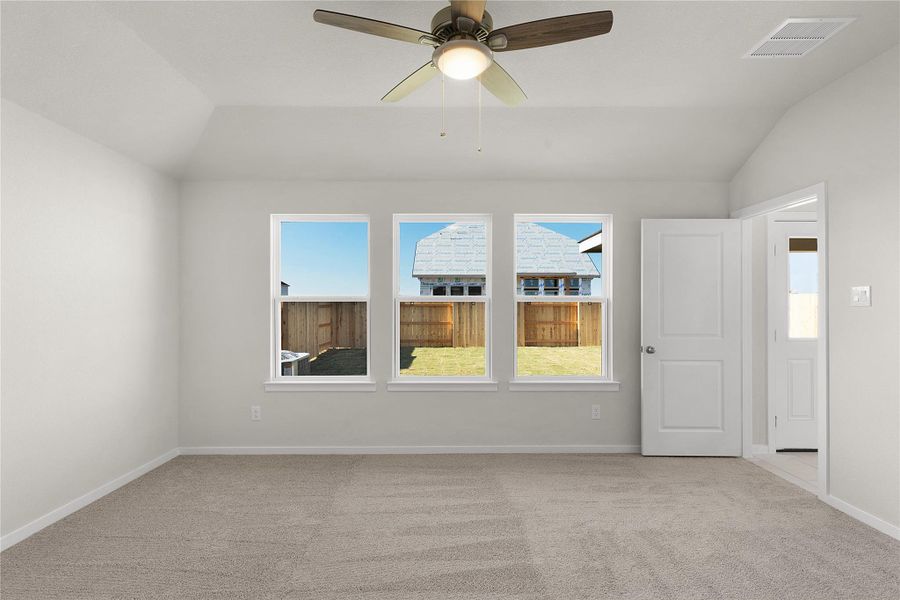 Unfurnished room featuring a ceiling fan, vaulted ceiling, light carpet, and plenty of natural light