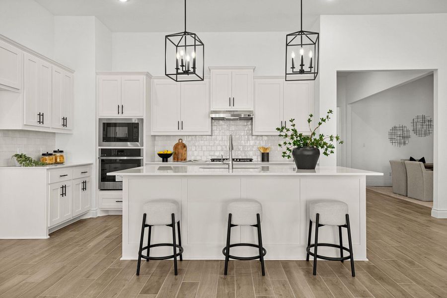 Kitchen with a kitchen island with sink, white cabinetry, wood finish floors, and stainless steel appliances