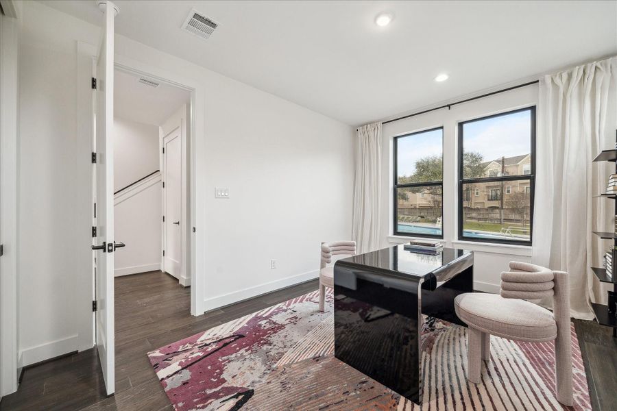 Spacious study with dual windows bringing in natural light and views of the surrounding community. The open layout and neutral palette provide flexibility for a variety of uses, while the proximity to a full bath enhances functionality. Thoughtful architectural details and clean lines continue the home’s cohesive contemporary design.