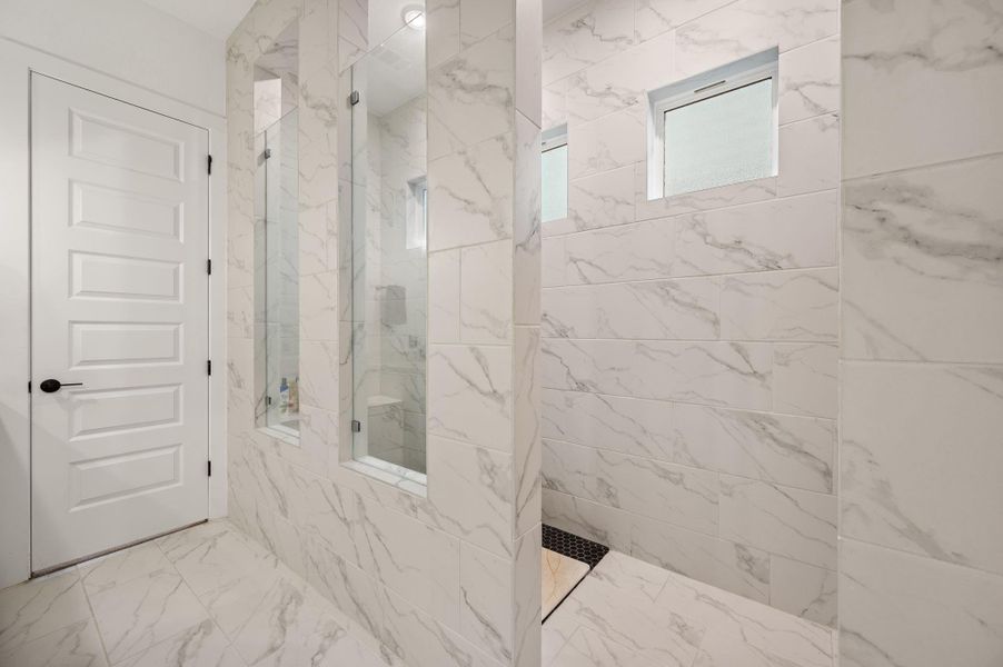 Massive walk-in shower with sitting benches on both sides of the shower