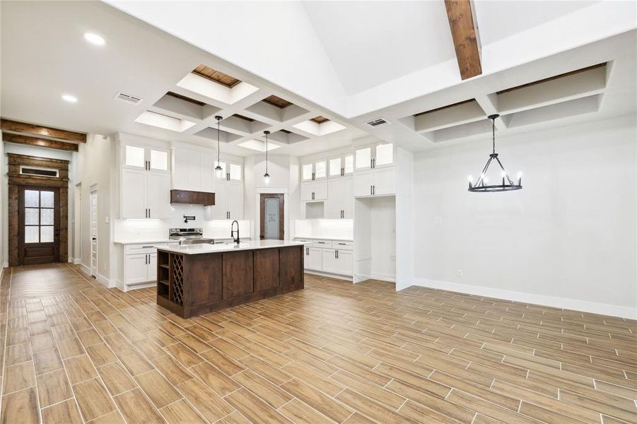 Kitchen with pendant lighting, white cabinetry, an inviting chandelier, and an island with sink