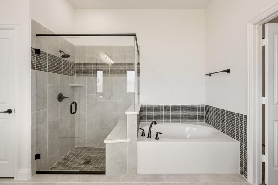 Master bathroom with glass-enclosed walk-in shower and soaking tub, gray tile accents and dark bronze fixtures Master bathroom with glass-enclosed walk-in shower and soaking tub, gray tile accents and dark bronze fixtures