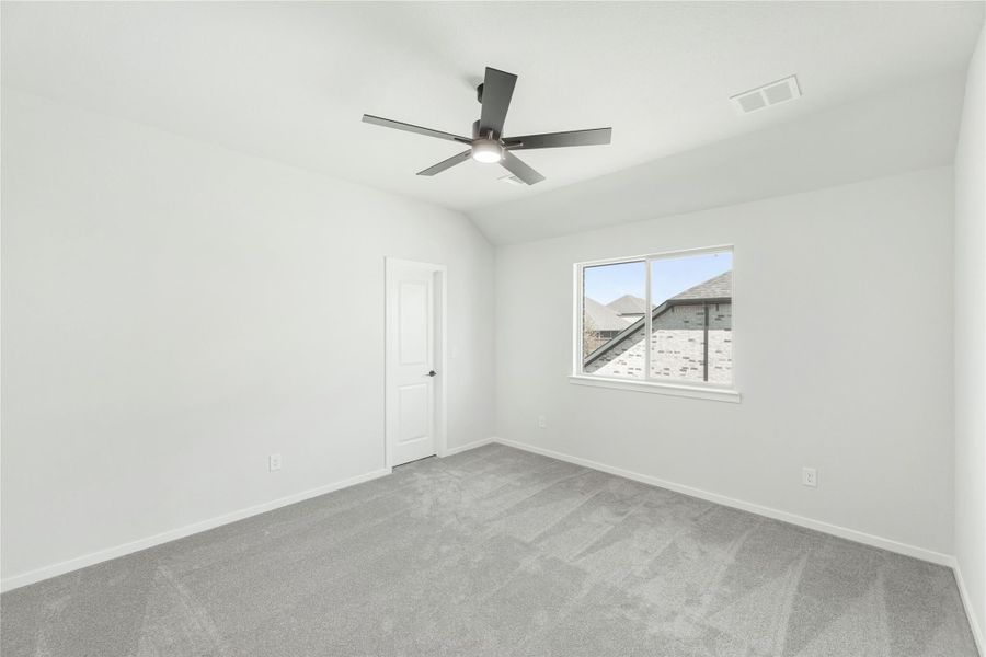 Empty bedroom with gray carpet, vaulted ceiling, ceiling fan, and single window Empty bedroom with gray carpet, vaulted ceiling, ceiling fan, and single window