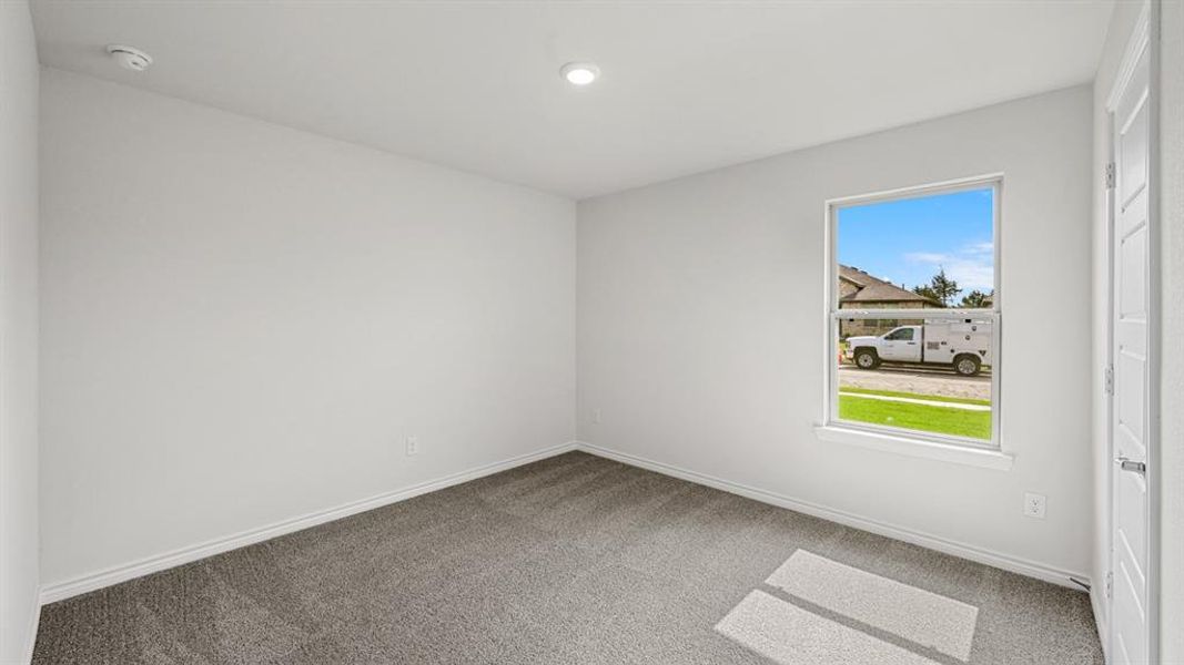 Room featuring neutral gray carpet flooring, white painted walls, a single-pane window, and a white interior door with a silver handle Room featuring neutral gray carpet flooring, white painted walls, a single-pane window, and a white interior door with a silver handle