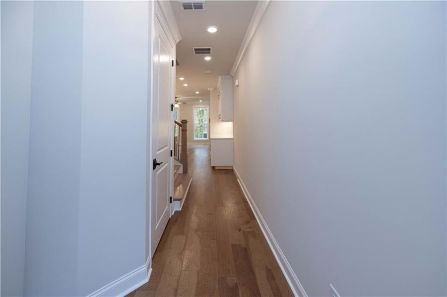 Hall with dark wood-style flooring, recessed lighting, and ornamental molding